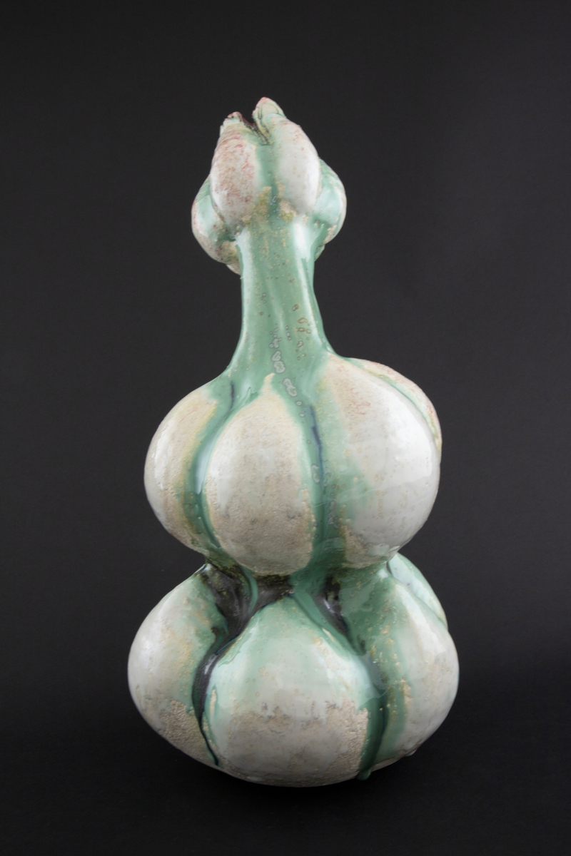 Håndmodellert skulptur i glasert steingods med delvis tiltende hode. Den har en organisk og asymmetrisk kalebassform som ender i en tulipanform med halvåpne kronblader. Keramikkskulpturen inngår i en installasjon bestående av 26 deler i ulike størrelser og med individuell utforming. De asymmetriske variasjonene gir et inntrykk av bevegelse, og den lett sykelige fargepaletten gir et uhyggelig og grotesk preg. Samtlige deler minner om kjøttetende planter.