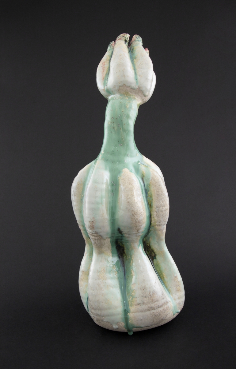 Håndmodellert skulptur i glasert steingods med oppreist holdning. Den har en organisk og asymmetrisk kalebassform som ender i en tulipanform med halvåpne kronblader. Keramikkskulpturen inngår i en installasjon bestående av 26 deler i ulike størrelser og med individuell utforming. De asymmetriske variasjonene gir et inntrykk av bevegelse, og den lett sykelige fargepaletten gir et uhyggelig og grotesk preg. Samtlige deler minner om kjøttetende planter.