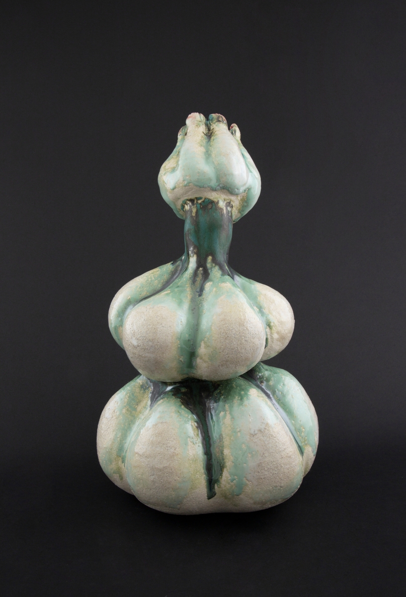 Håndmodellert skulptur i glasert steingods med lett tiltende hode. Den har en organisk og asymmetrisk kalebassform som ender i en tulipanform med halvåpne kronblader. Keramikkskulpturen inngår i en installasjon bestående av 26 deler i ulike størrelser og med individuell utforming. De asymmetriske variasjonene gir et inntrykk av bevegelse, og den lett sykelige fargepaletten gir et uhyggelig og grotesk preg. Samtlige deler minner om kjøttetende planter.