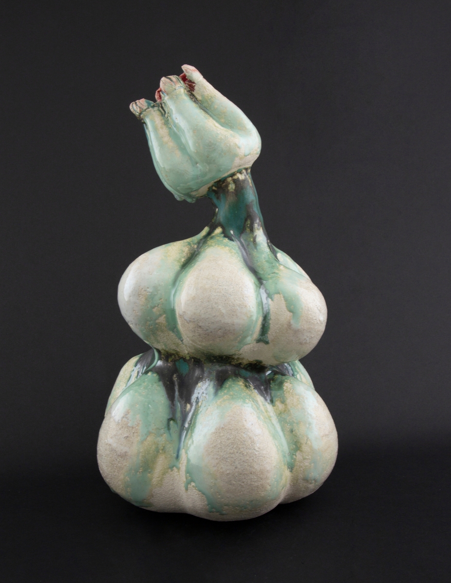 Håndmodellert skulptur i glasert steingods med lett tiltende hode. Den har en organisk og asymmetrisk kalebassform som ender i en tulipanform med halvåpne kronblader. Keramikkskulpturen inngår i en installasjon bestående av 26 deler i ulike størrelser og med individuell utforming. De asymmetriske variasjonene gir et inntrykk av bevegelse, og den lett sykelige fargepaletten gir et uhyggelig og grotesk preg. Samtlige deler minner om kjøttetende planter.