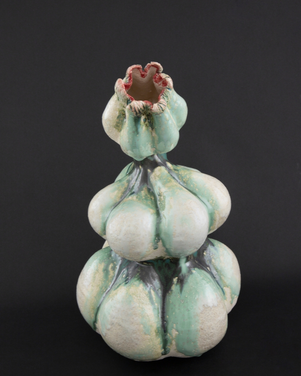 Håndmodellert skulptur i glasert steingods med lett tiltende hode. Den har en organisk og asymmetrisk kalebassform som ender i en tulipanform med halvåpne kronblader. Keramikkskulpturen inngår i en installasjon bestående av 26 deler i ulike størrelser og med individuell utforming. De asymmetriske variasjonene gir et inntrykk av bevegelse, og den lett sykelige fargepaletten gir et uhyggelig og grotesk preg. Samtlige deler minner om kjøttetende planter.