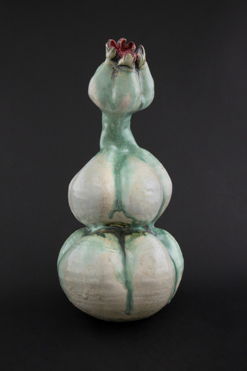 Håndmodellert skulptur i glasert steingods med oppreist holdning og litt tiltet hode. Den har en organisk og asymmetrisk kalebassform som ender i en tulipanform med halvåpne kronblader. Keramikkskulpturen inngår i en installasjon bestående av 26 deler i ulike størrelser og med individuell utforming. De asymmetriske variasjonene gir et inntrykk av bevegelse, og den lett sykelige fargepaletten gir et uhyggelig og grotesk preg. Samtlige deler minner om kjøttetende planter.