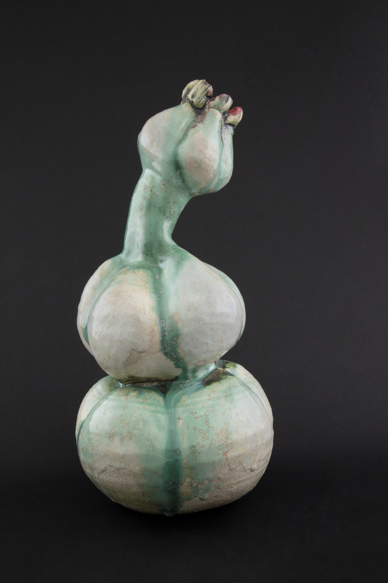 Håndmodellert skulptur i glasert steingods med oppreist holdning og litt tiltet hode. Den har en organisk og asymmetrisk kalebassform som ender i en tulipanform med halvåpne kronblader. Keramikkskulpturen inngår i en installasjon bestående av 26 deler i ulike størrelser og med individuell utforming. De asymmetriske variasjonene gir et inntrykk av bevegelse, og den lett sykelige fargepaletten gir et uhyggelig og grotesk preg. Samtlige deler minner om kjøttetende planter.