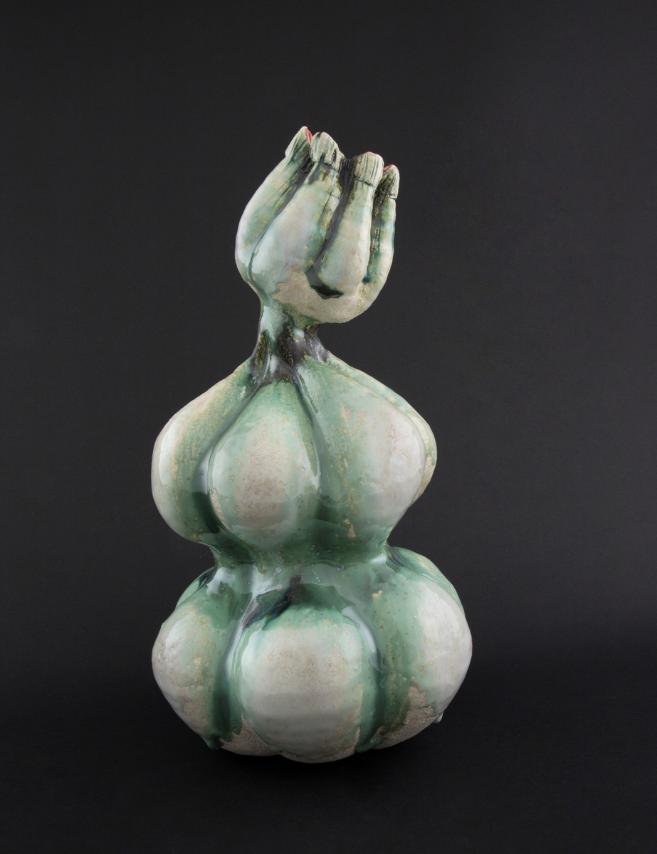 Håndmodellert skulptur i glasert steingods med oppreist holdning og litt tiltet hode. Den har en organisk og asymmetrisk kalebassform som ender i en tulipanform med halvåpne kronblader. Keramikkskulpturen inngår i en installasjon bestående av 26 deler i ulike størrelser og med individuell utforming. De asymmetriske variasjonene gir et inntrykk av bevegelse, og den lett sykelige fargepaletten gir et uhyggelig og grotesk preg. Samtlige deler minner om kjøttetende planter.