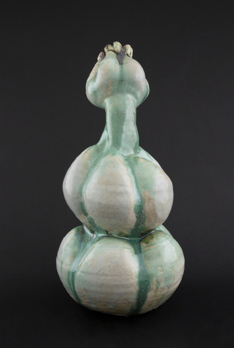 Håndmodellert skulptur i glasert steingods med oppreist holdning og litt tiltet hode. Den har en organisk og asymmetrisk kalebassform som ender i en tulipanform med halvåpne kronblader. Keramikkskulpturen inngår i en installasjon bestående av 26 deler i ulike størrelser og med individuell utforming. De asymmetriske variasjonene gir et inntrykk av bevegelse, og den lett sykelige fargepaletten gir et uhyggelig og grotesk preg. Samtlige deler minner om kjøttetende planter.