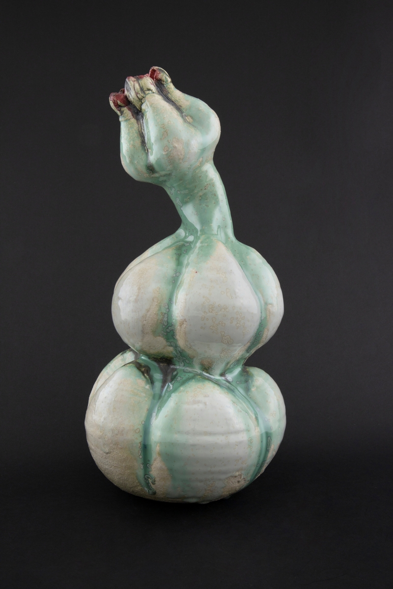 Håndmodellert skulptur i glasert steingods med oppreist holdning og litt tiltet hode. Den har en organisk og asymmetrisk kalebassform som ender i en tulipanform med halvåpne kronblader. Keramikkskulpturen inngår i en installasjon bestående av 26 deler i ulike størrelser og med individuell utforming. De asymmetriske variasjonene gir et inntrykk av bevegelse, og den lett sykelige fargepaletten gir et uhyggelig og grotesk preg. Samtlige deler minner om kjøttetende planter.