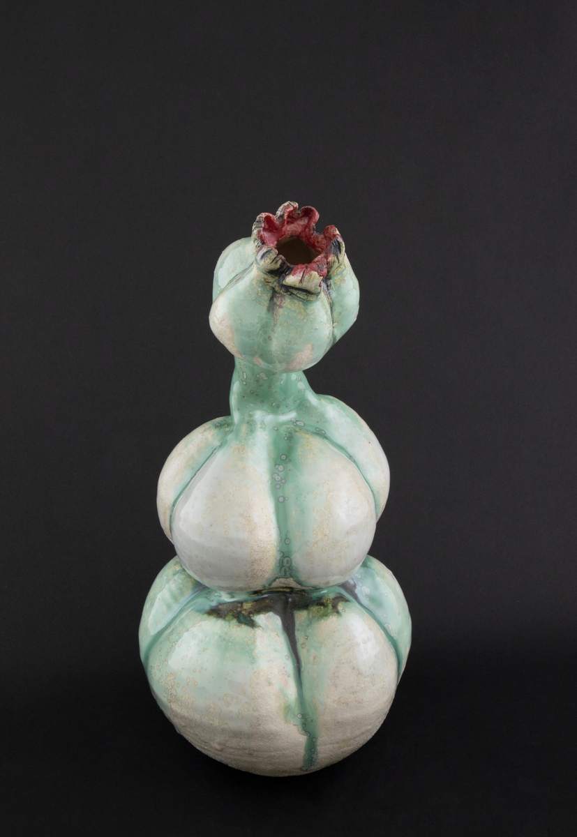 Håndmodellert skulptur i glasert steingods med oppreist holdning og litt tiltet hode. Den har en organisk og asymmetrisk kalebassform som ender i en tulipanform med halvåpne kronblader. Keramikkskulpturen inngår i en installasjon bestående av 26 deler i ulike størrelser og med individuell utforming. De asymmetriske variasjonene gir et inntrykk av bevegelse, og den lett sykelige fargepaletten gir et uhyggelig og grotesk preg. Samtlige deler minner om kjøttetende planter.