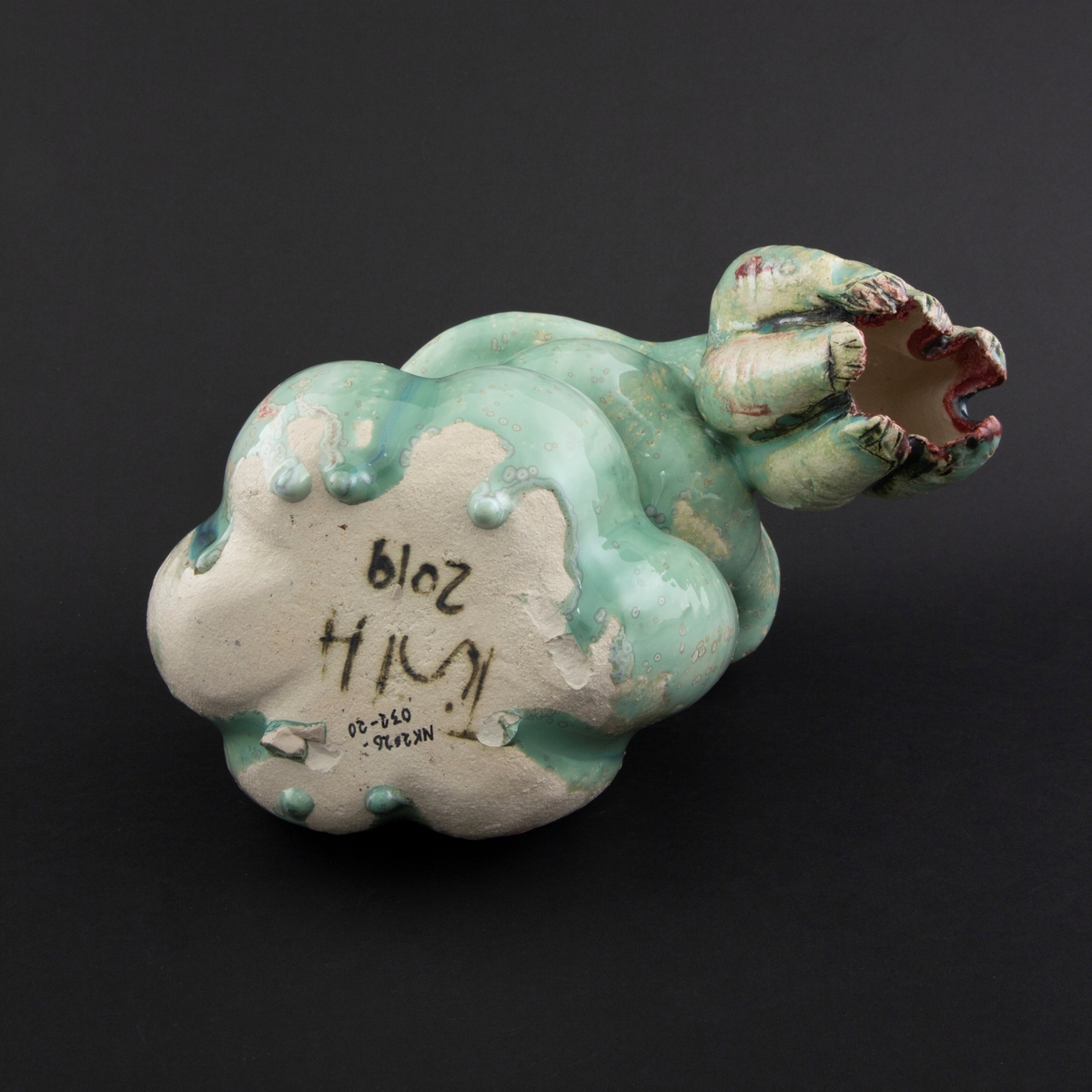 Håndmodellert skulptur i glasert steingods i liggende positur. Den har en organisk og asymmetrisk kalebassform som ender i en tulipanform med halvåpne kronblader. Keramikkskulpturen inngår i en installasjon bestående av 26 deler i ulike størrelser og med individuell utforming. De asymmetriske variasjonene gir et inntrykk av bevegelse, og den lett sykelige fargepaletten gir et uhyggelig og grotesk preg. Samtlige deler minner om kjøttetende planter.