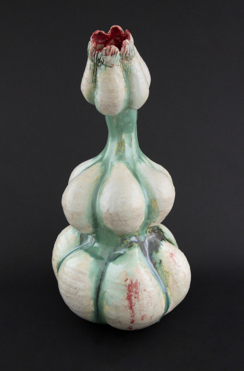 Håndmodellert skulptur i glasert steingods med litt svai kropp. Den har en organisk og asymmetrisk kalebassform som ender i en tulipanform med halvåpne kronblader. Keramikkskulpturen inngår i en installasjon bestående av 26 deler i ulike størrelser og med individuell utforming. De asymmetriske variasjonene gir et inntrykk av bevegelse, og den lett sykelige fargepaletten gir et uhyggelig og grotesk preg. Samtlige deler minner om kjøttetende planter.