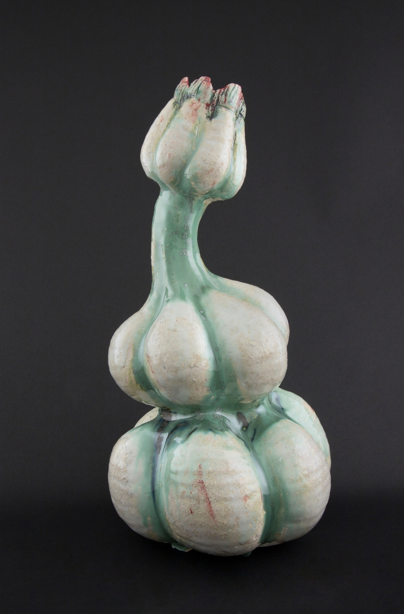 Håndmodellert skulptur i glasert steingods med litt svai kropp. Den har en organisk og asymmetrisk kalebassform som ender i en tulipanform med halvåpne kronblader. Keramikkskulpturen inngår i en installasjon bestående av 26 deler i ulike størrelser og med individuell utforming. De asymmetriske variasjonene gir et inntrykk av bevegelse, og den lett sykelige fargepaletten gir et uhyggelig og grotesk preg. Samtlige deler minner om kjøttetende planter.