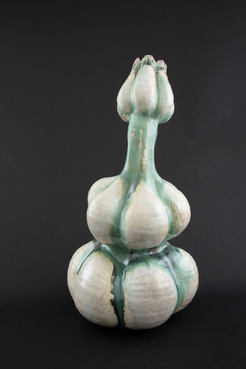 Håndmodellert skulptur i glasert steingods med litt svai kropp. Den har en organisk og asymmetrisk kalebassform som ender i en tulipanform med halvåpne kronblader. Keramikkskulpturen inngår i en installasjon bestående av 26 deler i ulike størrelser og med individuell utforming. De asymmetriske variasjonene gir et inntrykk av bevegelse, og den lett sykelige fargepaletten gir et uhyggelig og grotesk preg. Samtlige deler minner om kjøttetende planter.