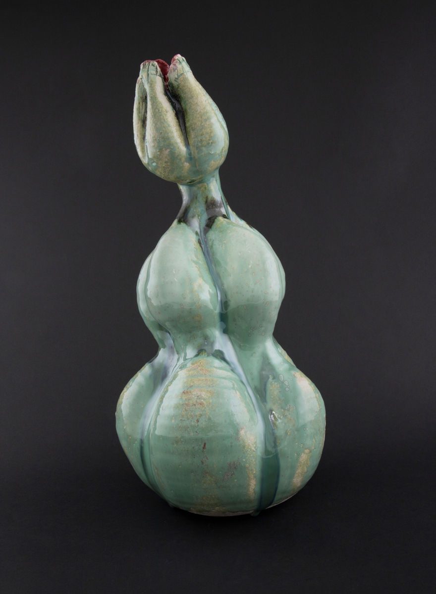 Håndmodellert skulptur i glasert steingods med oppreist holdning. Den har en organisk og asymmetrisk kalebassform som ender i en tulipanform med halvåpne kronblader. Keramikkskulpturen inngår i en installasjon bestående av 26 deler i ulike størrelser og med individuell utforming. De asymmetriske variasjonene gir et inntrykk av bevegelse, og den lett sykelige fargepaletten gir et uhyggelig og grotesk preg. Samtlige deler minner om kjøttetende planter.