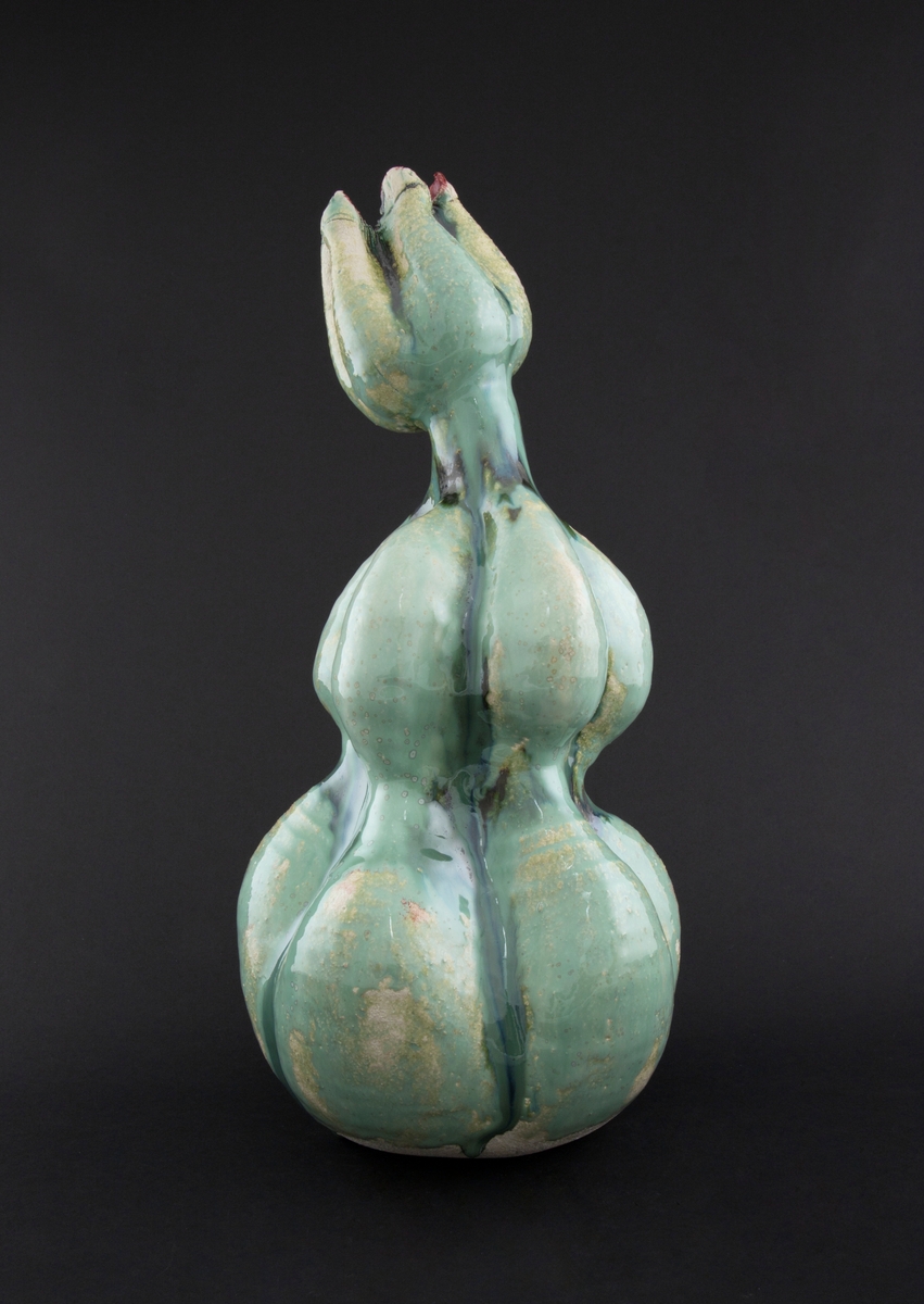 Håndmodellert skulptur i glasert steingods med oppreist holdning. Den har en organisk og asymmetrisk kalebassform som ender i en tulipanform med halvåpne kronblader. Keramikkskulpturen inngår i en installasjon bestående av 26 deler i ulike størrelser og med individuell utforming. De asymmetriske variasjonene gir et inntrykk av bevegelse, og den lett sykelige fargepaletten gir et uhyggelig og grotesk preg. Samtlige deler minner om kjøttetende planter.