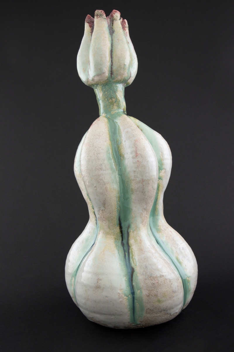 Håndmodellert skulptur i glasert steingods med oppreist holdning. Den har en organisk og asymmetrisk kalebassform som ender i en tulipanform med halvåpne kronblader. Keramikkskulpturen inngår i en installasjon bestående av 26 deler i ulike størrelser og med individuell utforming. De asymmetriske variasjonene gir et inntrykk av bevegelse, og den lett sykelige fargepaletten gir et uhyggelig og grotesk preg. Samtlige deler minner om kjøttetende planter.