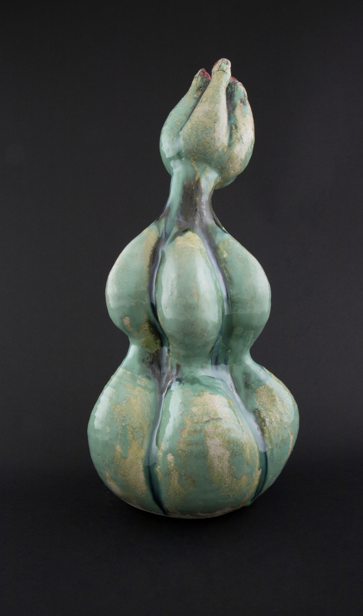 Håndmodellert skulptur i glasert steingods med oppreist holdning. Den har en organisk og asymmetrisk kalebassform som ender i en tulipanform med halvåpne kronblader. Keramikkskulpturen inngår i en installasjon bestående av 26 deler i ulike størrelser og med individuell utforming. De asymmetriske variasjonene gir et inntrykk av bevegelse, og den lett sykelige fargepaletten gir et uhyggelig og grotesk preg. Samtlige deler minner om kjøttetende planter.