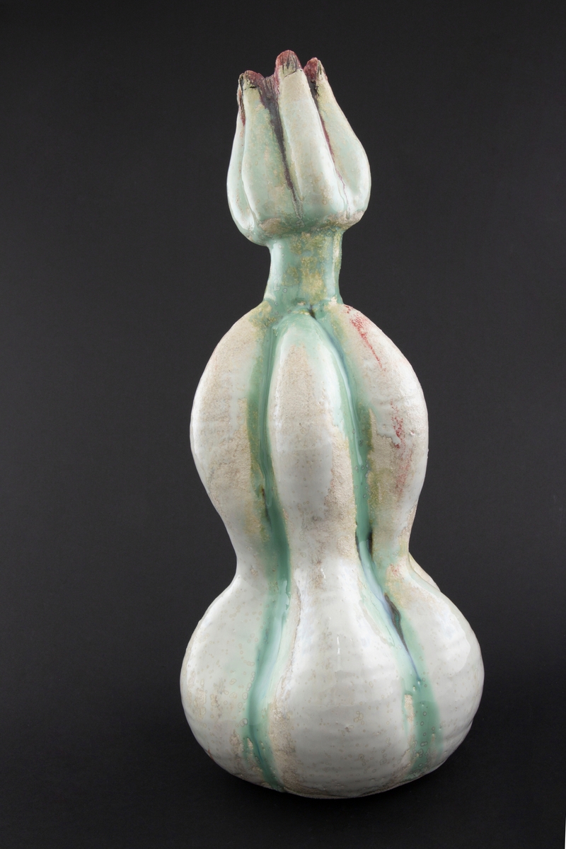 Håndmodellert skulptur i glasert steingods med oppreist holdning. Den har en organisk og asymmetrisk kalebassform som ender i en tulipanform med halvåpne kronblader. Keramikkskulpturen inngår i en installasjon bestående av 26 deler i ulike størrelser og med individuell utforming. De asymmetriske variasjonene gir et inntrykk av bevegelse, og den lett sykelige fargepaletten gir et uhyggelig og grotesk preg. Samtlige deler minner om kjøttetende planter.