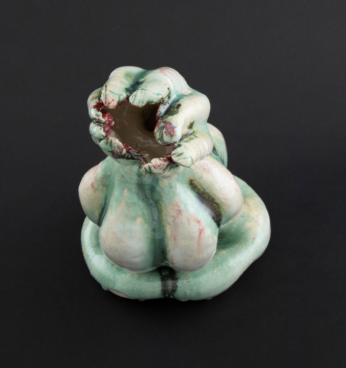 Håndmodellert skulptur i glasert steingods med henslengt kropp. Den har en organisk og asymmetrisk kalebassform som ender i en tulipanform med halvåpne kronblader. Keramikkskulpturen inngår i en installasjon bestående av 26 deler i ulike størrelser og med individuell utforming. De asymmetriske variasjonene gir et inntrykk av bevegelse, og den lett sykelige fargepaletten gir et uhyggelig og grotesk preg. Samtlige deler minner om kjøttetende planter.