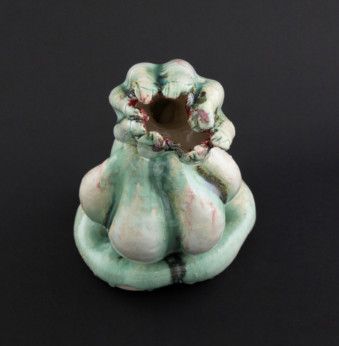 Håndmodellert skulptur i glasert steingods med henslengt kropp. Den har en organisk og asymmetrisk kalebassform som ender i en tulipanform med halvåpne kronblader. Keramikkskulpturen inngår i en installasjon bestående av 26 deler i ulike størrelser og med individuell utforming. De asymmetriske variasjonene gir et inntrykk av bevegelse, og den lett sykelige fargepaletten gir et uhyggelig og grotesk preg. Samtlige deler minner om kjøttetende planter.