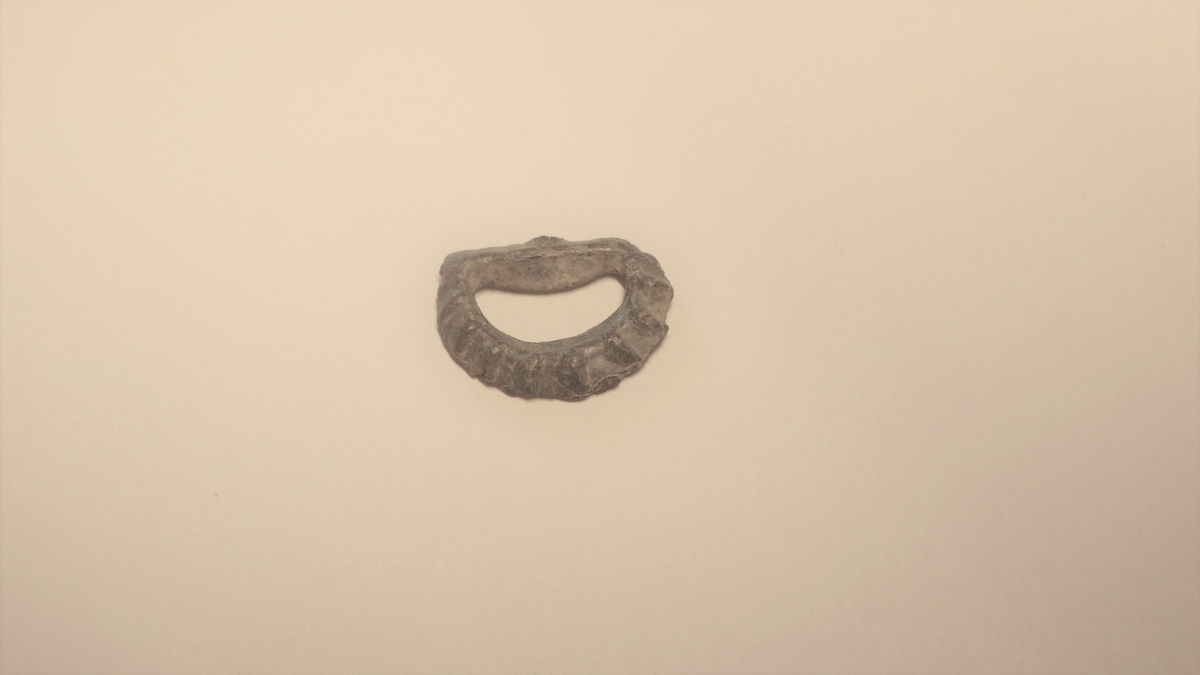 MALV: B. 17 MM, STØPT, HALVSIRKEL. DEN ENE SIDEN HAR RADIALE RIFLER. DEN ANDRE SIDEN ER FLAT. LIGGER SAMMEN MED BESLAG. BELTE. 
