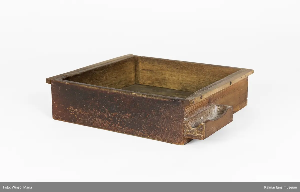 KLM 24993:4:1-6. Arbetsbord, urmakarbord. 6 delar. Möbeln har varit platsbyggd och går ej att montera ihop. Av trä, målad med röd färg. Bordsskiva (:1) med rektangulär form och avfasade kortsidor. På undersidan plats för två utdragslådor. På ovansidan till höger sitter ett skruvstäd av järn fastskruvat. Till bordsskivan finns två lösa ben (:2-:3) som upptill suttit fast på främre delen av skivans undersida, fötterna har varit fastspikade i en vägg. Till bordet hör också ett hyllplan (:4) som suttit under bordsskivan, vilande på benen. Till bordet finns två utdragslådor (:5-:6).