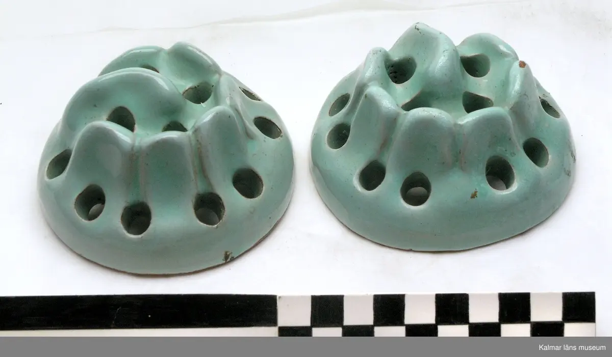 KLM 41861 Blomhållare, 2 st, keramik. Rund, oregelbundet toppig med flera små runda hål, glaserad i ljusgrönt. Använd placerad i botten på en vas eller skål, i hålen sticks blomstjälkar ner.