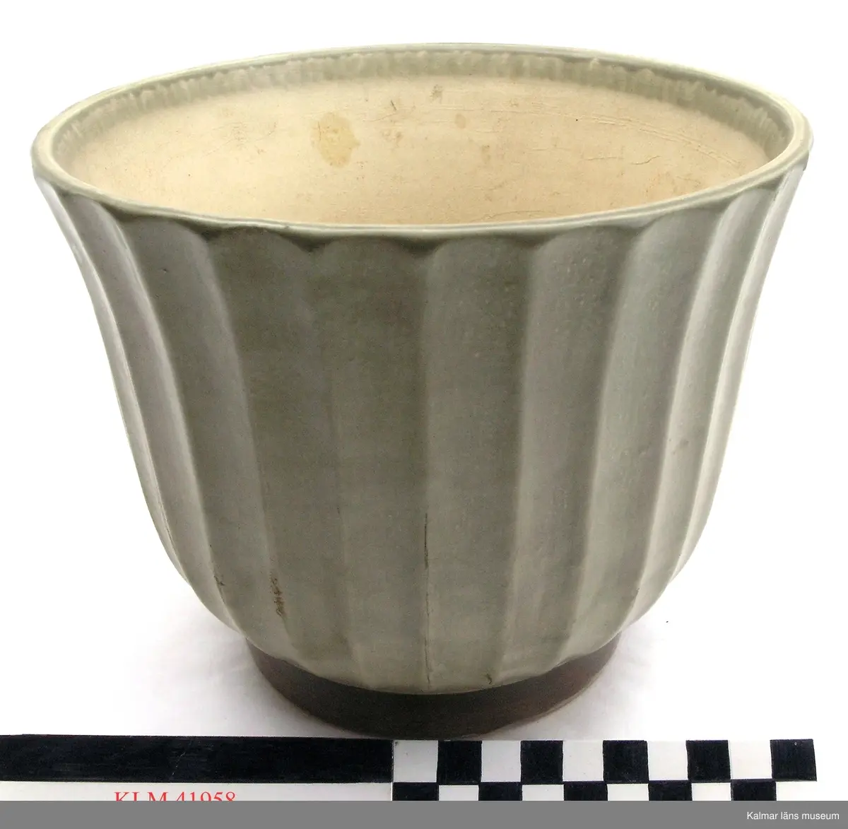 KLM 41958. Ytterkruka, keramik. Rund, på låg fot, vidgande sig uppåt. Utsidan med längsgående räfflor samt glaserad grågrön. Insidan gulvit. På undersidan märkt ED,  Bo/8.