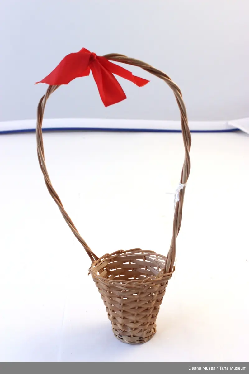 Liten blomster kurv av strå med rød sløyfe.
