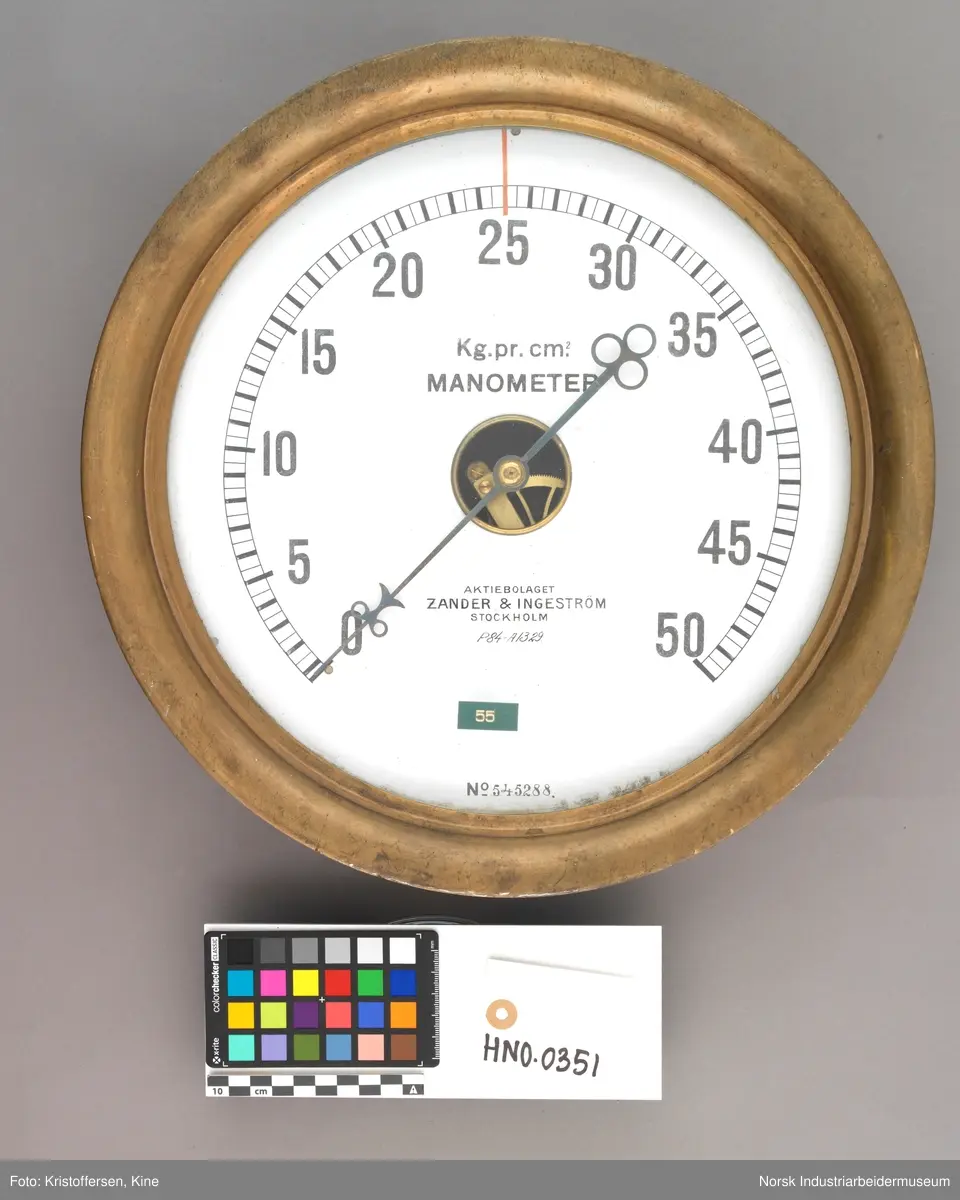 Manometer for kjøleanlegg nr. 41112.
Sirkulært måleinsturment i messingskall. Buet innhakk i messingen rundt glasset. Måleskiven med pil viser tall fra 0-50. Pilen har to sirkler i tupp og tre sirkler i enden. Åpent inn til tannhjulene i midten hvor pilen er festet.