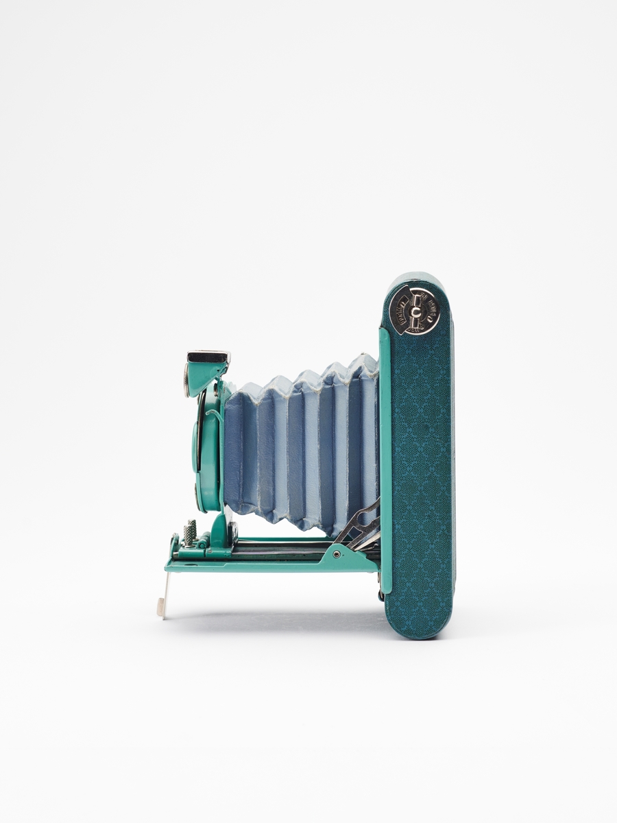 Petite "Step Pattern" - Vest Pocket Kodak Model B tilhører Vest Pocket-serien, en populær serie foldekameraer, produsert av Eastman Kodak Co. fra 1912-1935. Petite-kameraene kom i en rekke ulike farger og mønstre.  
Kameraet lager 4.5x6 cm. bilder på 127 film.