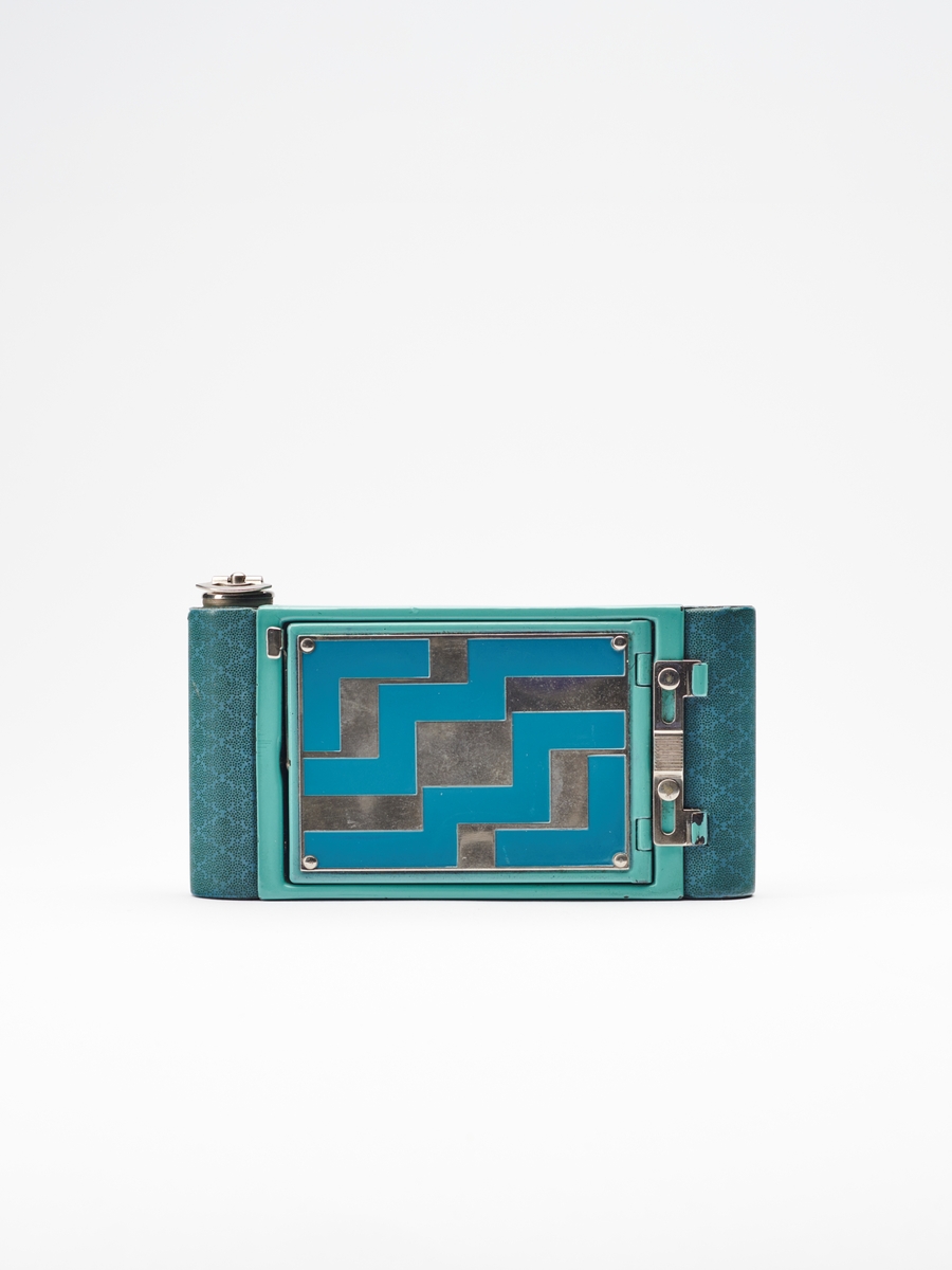 Petite "Step Pattern" - Vest Pocket Kodak Model B tilhører Vest Pocket-serien, en populær serie foldekameraer, produsert av Eastman Kodak Co. fra 1912-1935. Petite-kameraene kom i en rekke ulike farger og mønstre.  
Kameraet lager 4.5x6 cm. bilder på 127 film.