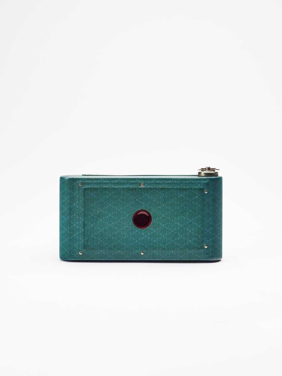 Petite "Step Pattern" - Vest Pocket Kodak Model B tilhører Vest Pocket-serien, en populær serie foldekameraer, produsert av Eastman Kodak Co. fra 1912-1935. Petite-kameraene kom i en rekke ulike farger og mønstre.  
Kameraet lager 4.5x6 cm. bilder på 127 film.
