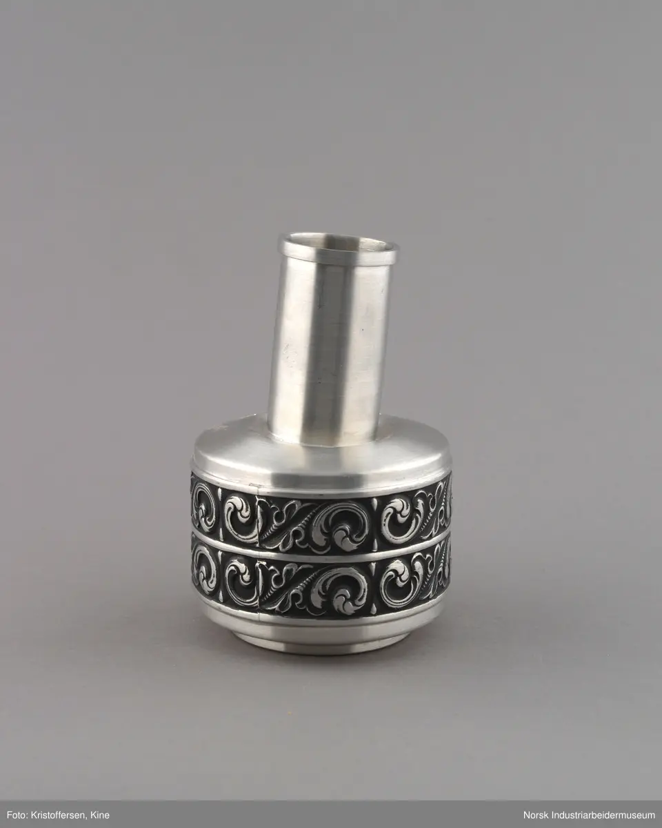 Vase eller pokal ned gravert innskrift til Bondeungdomslaget Maana i norsk tinn. Vasen er sirkulær med repeterende ornamentikk på to langsgående bånd rundt vasen. Hals er smal og sirkulær