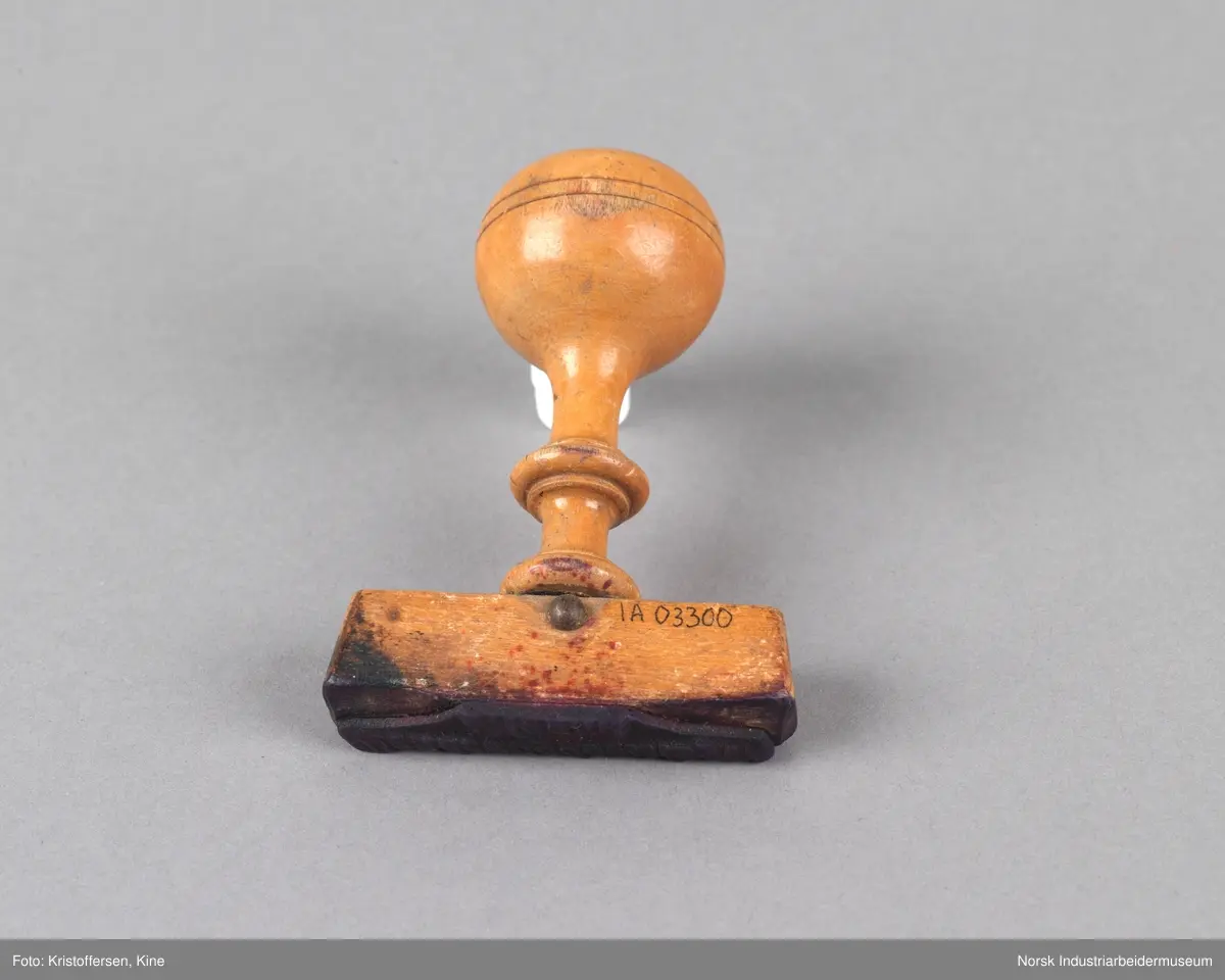 Stempel i tre med rundt håndtak og tverrgående stempelhode. Stempelpute med utheving av skriften "Bondeungdomslaget Maana".