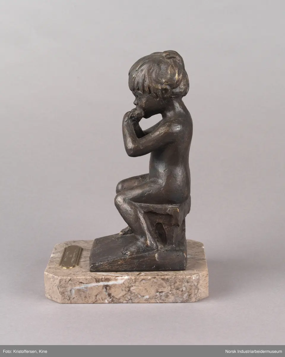 Tinn kommunes kulturpris, "Liten Ida" av kunstner Kjell Grette Christensen. Bronseskulptur av liten jente som sitter på en krakk og spiser noe med begge hendene. Skulpturen er festet på en firkantet steinplate uten hjørner. På steinplaten er det festet en plakett for Tinn kommunes kulturpris