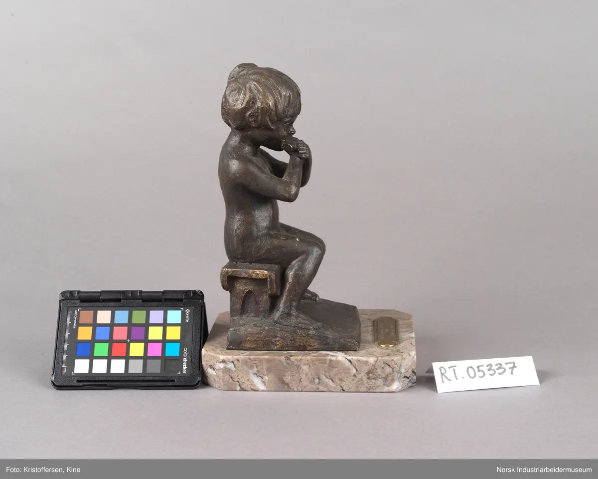 Tinn kommunes kulturpris, "Liten Ida" av kunstner Kjell Grette Christensen. Bronseskulptur av liten jente som sitter på en krakk og spiser noe med begge hendene. Skulpturen er festet på en firkantet steinplate uten hjørner. På steinplaten er det festet en plakett for Tinn kommunes kulturpris