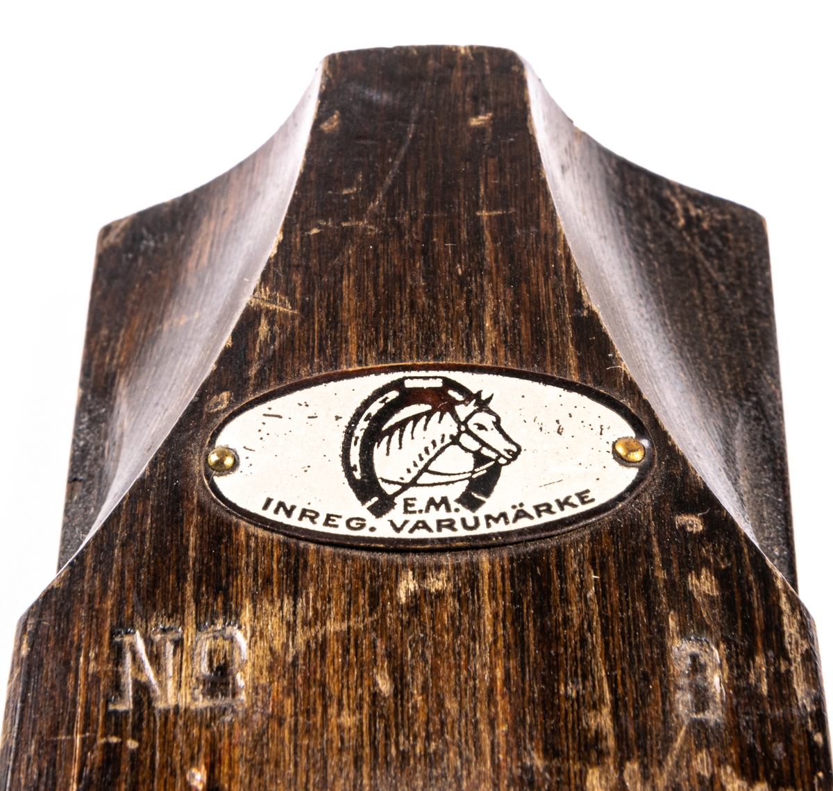 Skidbindningsprov. Vit metallegering på underlag av mörkbrunfärgat trä. På ovasidan Elof Malmbergs firmamärke i metall. Rund metallkantad etikett med skriften "2001 M   N. 7/75" Märke på metalldelen "HOBBY".