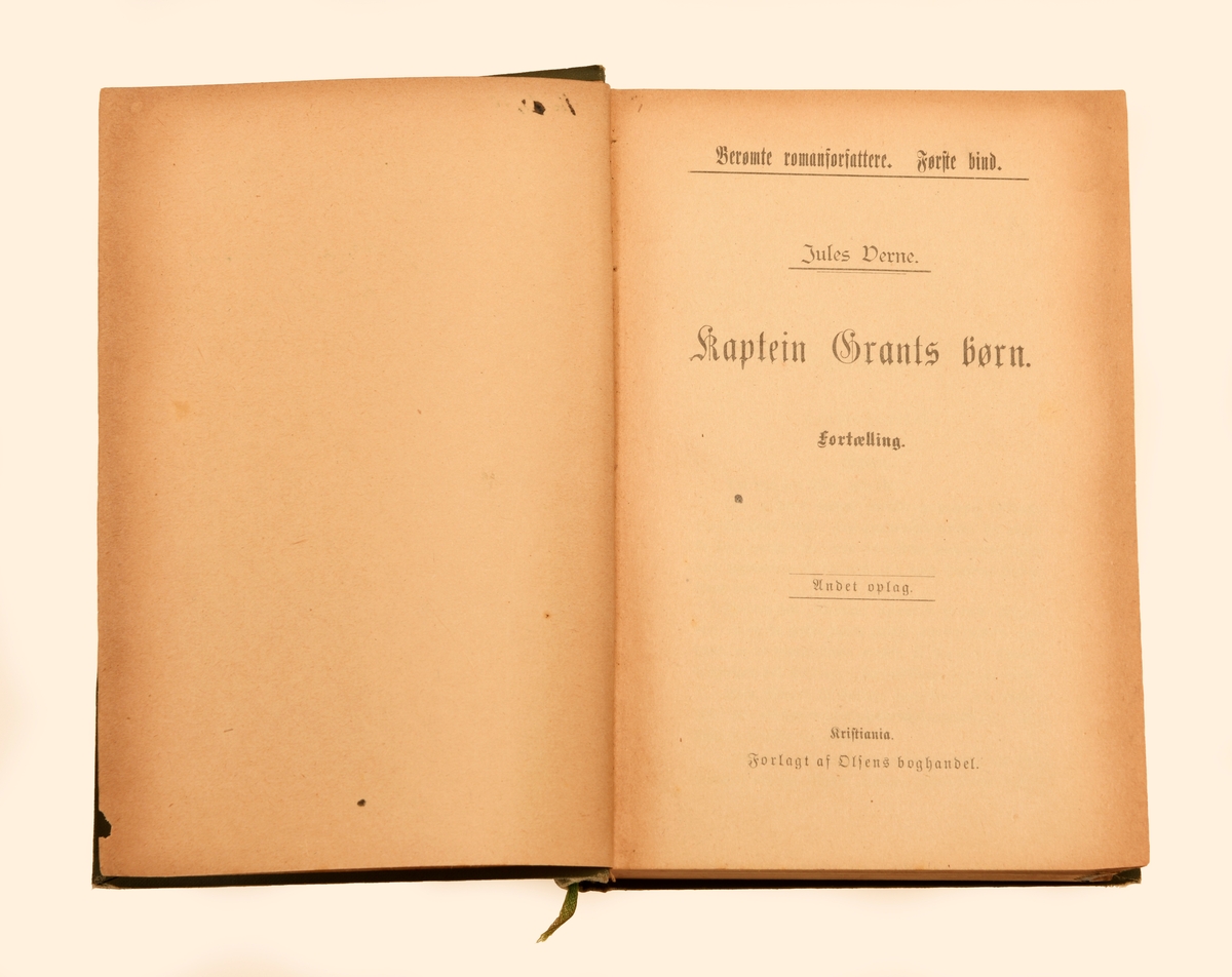 Boken "Kaptein Grants Børn" av Jules Verne. Boken er på 736 sider fordelt på 3 deler. Første del er inndelt i 24 kapitler, andre del i 22 kapitler og tredje del i 19 kapitler. Boken har gotisk skrift og er uten illustrasjoner. Til ryggen er det festet en tråd som kan brukes som bokmerke. Boken har stive permer som er trukket med grønt overtrekkspapir. På forsiden er det et illustrasjonsbilde i svart og grønt som forestiller tre båter på havet. Det er også bladranker i svart og gull samt tekst. På ryggen er det tekst og geometriske figurer/mønster. På første blad er det skrevet med penn (eier, sted og årstall samt pris). For mer informasjon om boken se foto av tittelbladet.