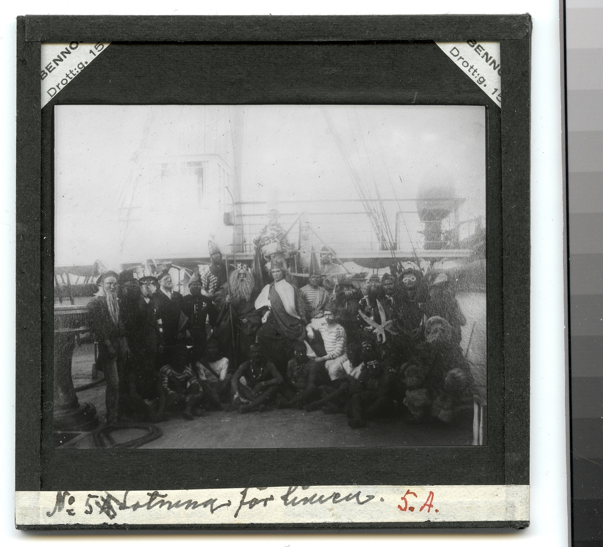 Bilden föreställer en grupp fantasifull utklädda sjömän som har samlats på däck inför neptunifesten vid passerandet av linjen den 21 jan 1884 ombord på fregatten Vanadis under hennes världsomsegling 1883-85.