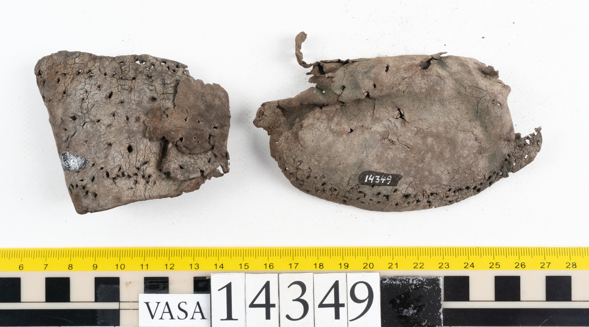 Sex delar från sko. Ett sidostycke med en kvarsittande bit av slejfen samt fem delar från skobotten i form av sulor mm. Lädret är spaltat och mycket sprött.