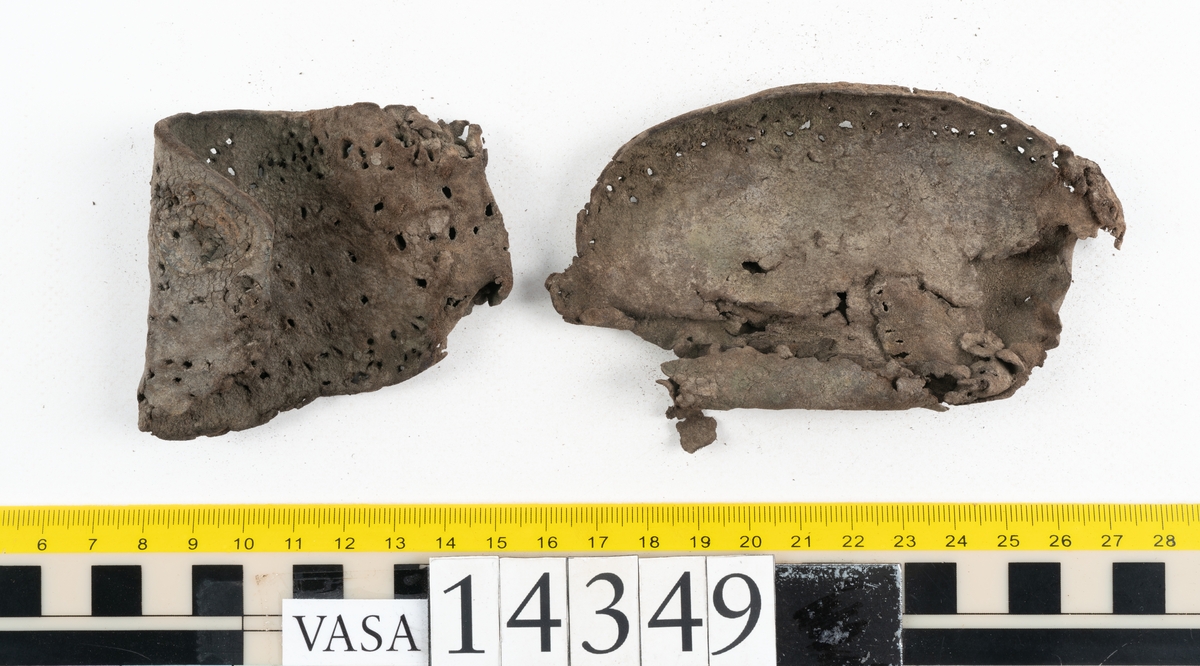 Sex delar från sko. Ett sidostycke med en kvarsittande bit av slejfen samt fem delar från skobotten i form av sulor mm. Lädret är spaltat och mycket sprött.