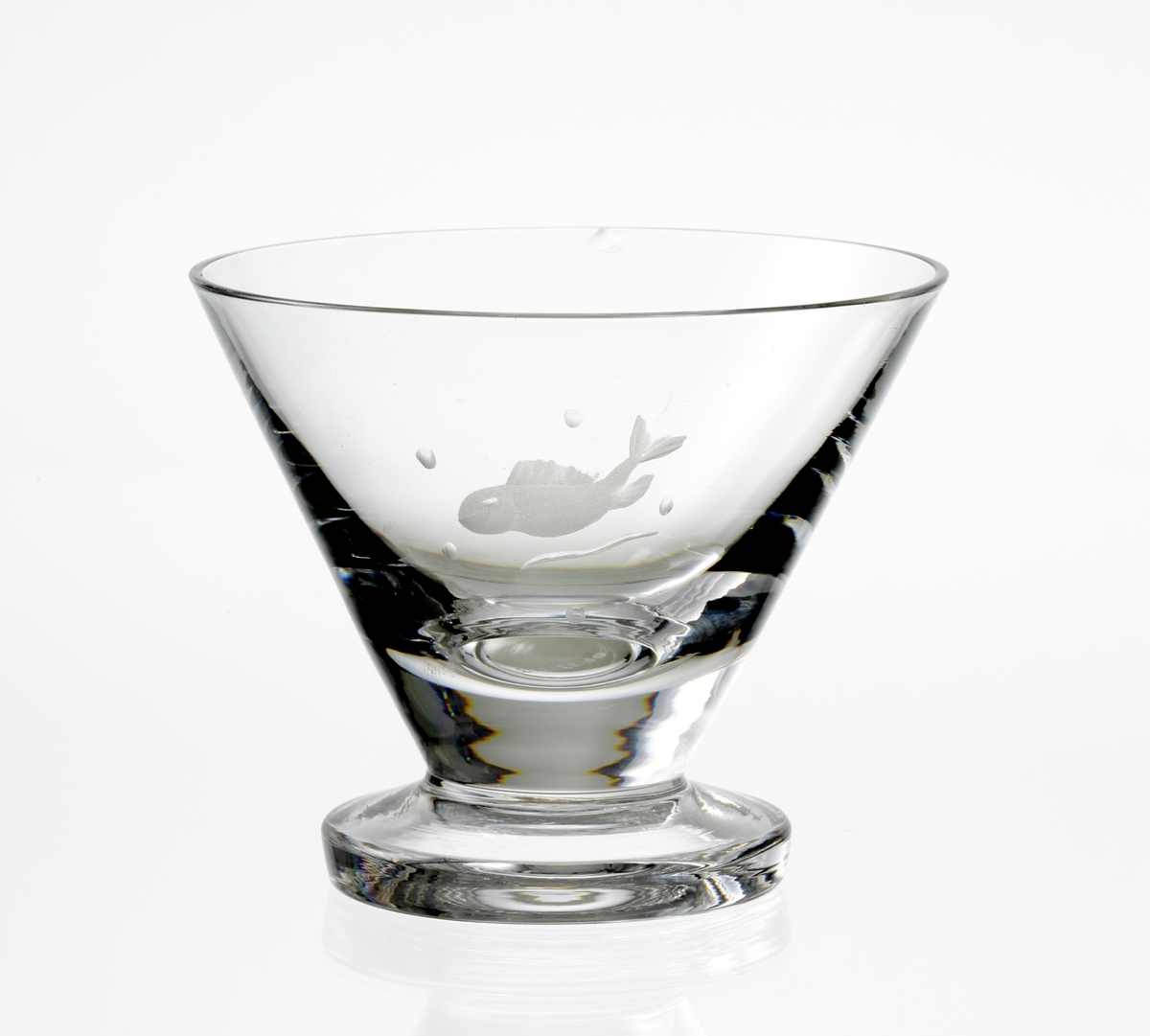 Design: Nils Landberg.
Madeiraglas. Konande kupa med graverad fisk. Cylindrisk fot.
Fabriksmärke: blå botten med guldtext.