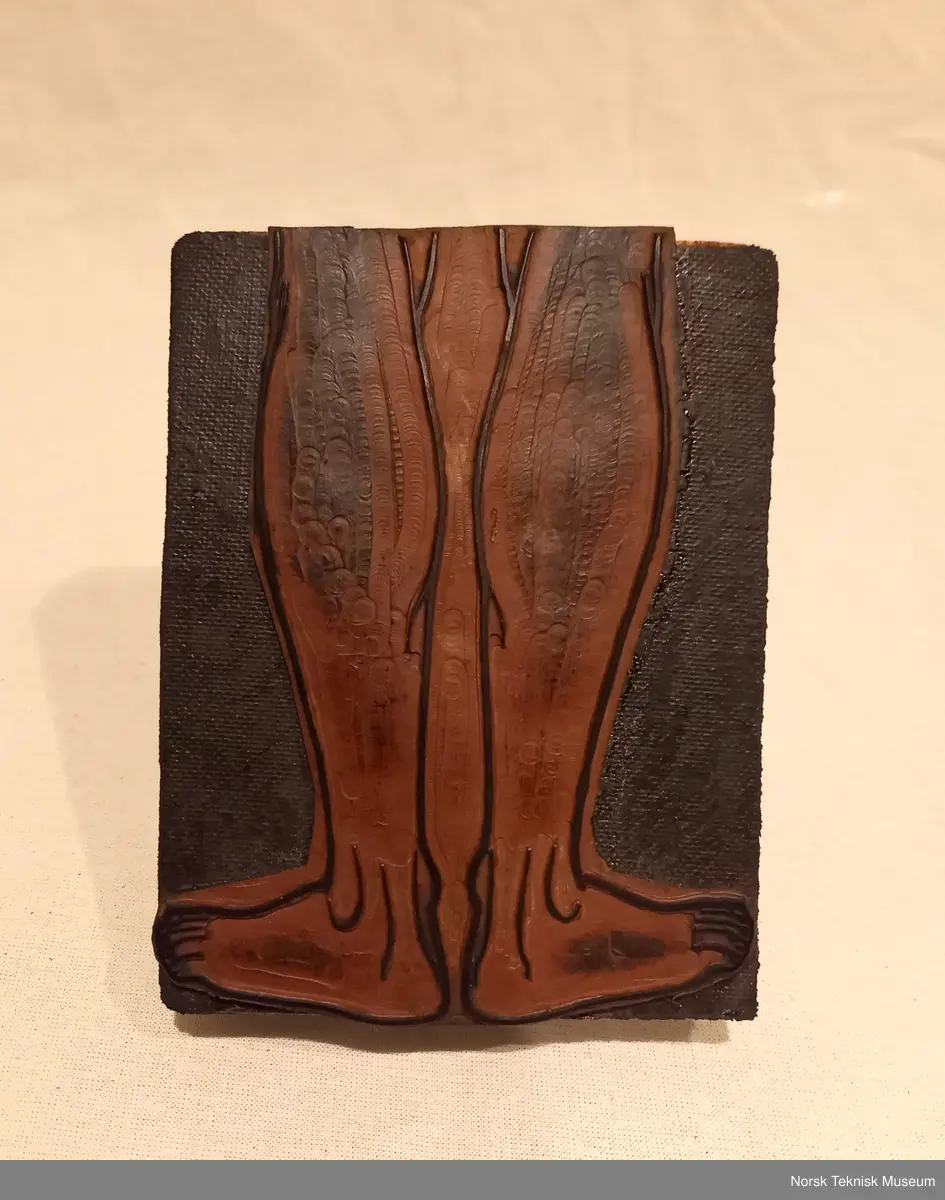 Stempel av tre med påklistret gummipute med motiv av begge føtter og legger bakfra. Håndtak i tre.