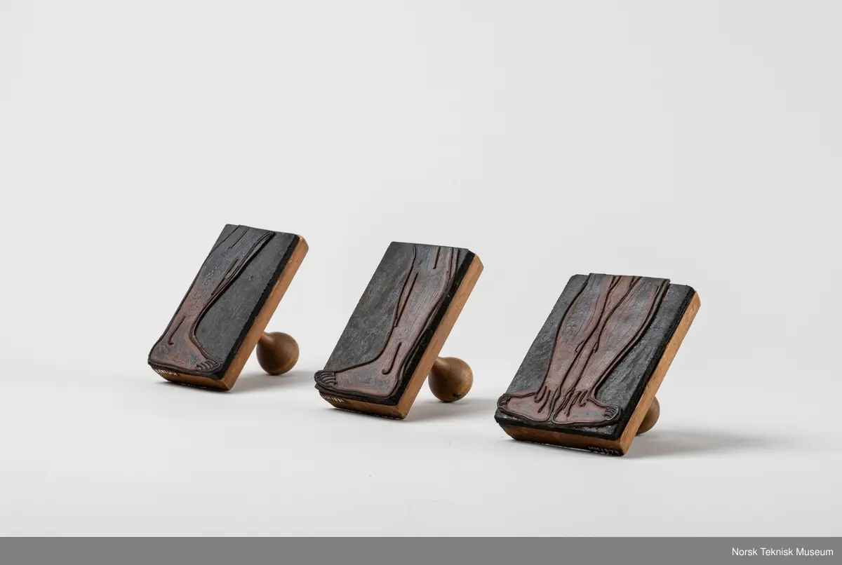 Stempel av tre med påklistret gummipute med motiv av begge føtter og legger bakfra. Håndtak i tre.