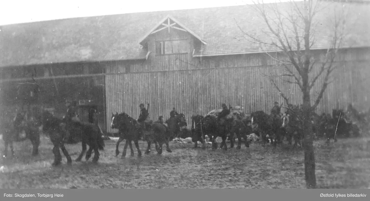 Fra gården Salmonrud i Eidsberg i april 1940, kaptein Rolf Graffs batteri under tilbaketrekning fra Fossum. Mange soldater på gårdstun, uthus i bakgrunnen.