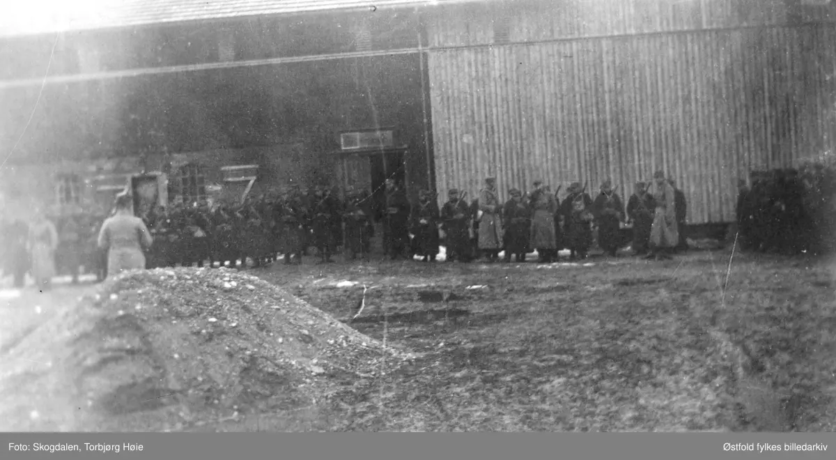 Fra gården Salmonrud i Eidsberg i april 1940, kaptein Rolf Graffs batteri under tilbaketrekning fra Fossum. Mange soldater til hest på gårdstunet. I bakgrunnen uthus.