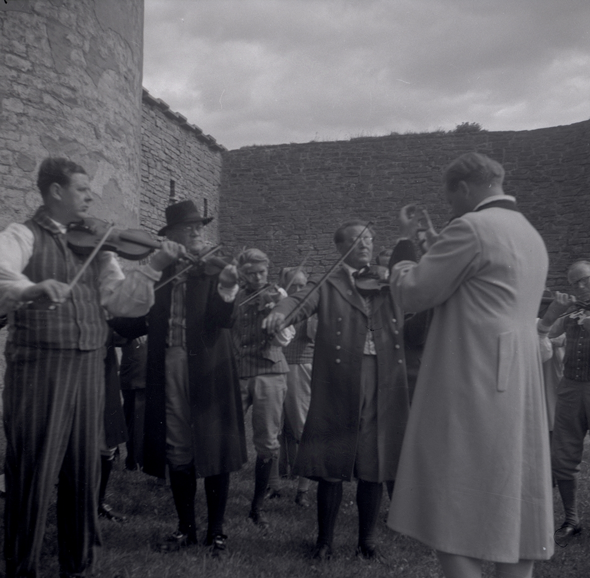 En orkester som spelar violin och folk som dansar i folkdräkter på Kalmar slott.