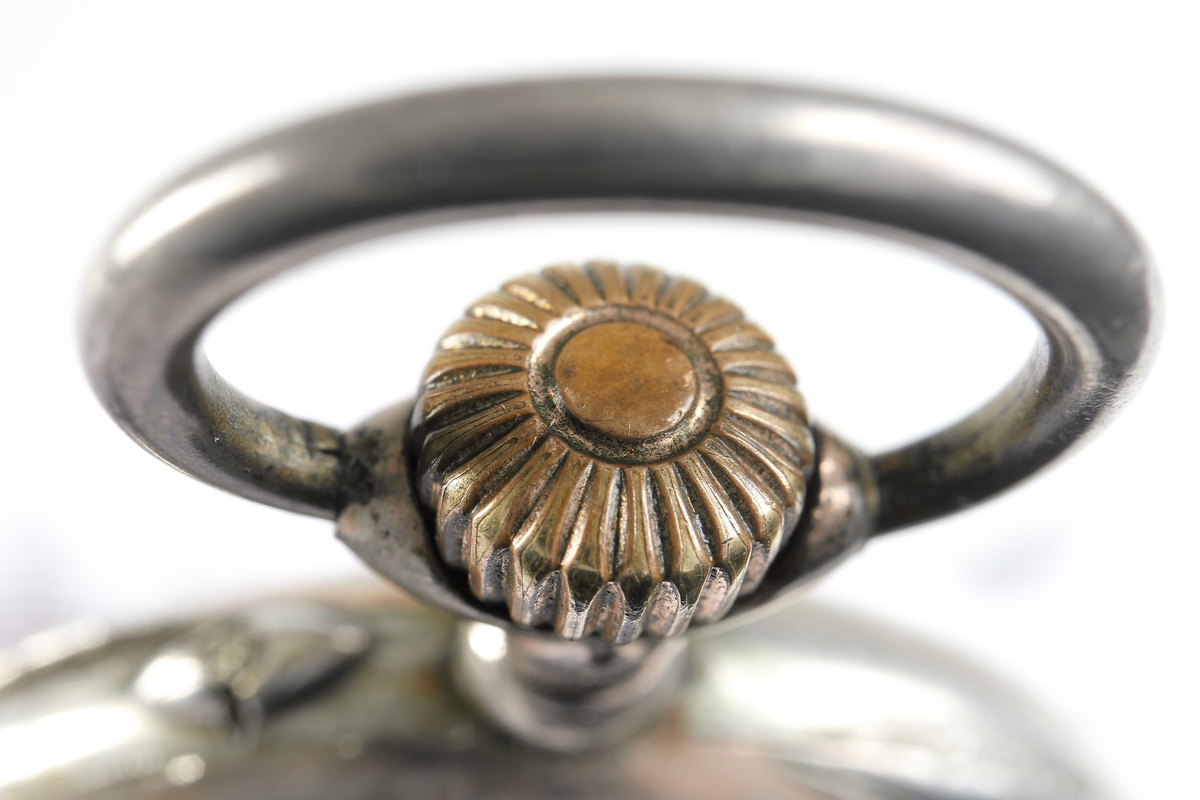 Fickur i silver som dras upp med krona. Runt kronan finns en bygel för att fästa en klockkedja. Den främre boetten har ett glas monterat framför urtavlan som består av vit emalj. Visarna är utsirade i guldfärg, och nedtill en mindre urtavla för sekundvisning. Bakboetten har ett mönstrat motiv liknande det svenska riksvapnet med två lejon på vardera sidan om en sköld krönt med en krona. Boettens ytterkanter är guldförgyllda. Ytterboettens insida har en stämpel liknande en halvmåne och en kungakrona, samt en större och en mindre som liknar en orre. Vidare finns numret "304070" och "0.800" inramat. Även "GALONNE" finns stämplat och siffran "11". Innerboettens utsida har ett graverat mönster bestående av ett liggande lejon med en sköld med de tre svenska kronorna vid sidan om. Vidare finns texten "1/2 CHRONOMETRE REMONTOIR SPIRAL BREGUET" och "CHATON OR 19 RUBIS" samt "BALANCIER COMPENSSÉ". Innerboettens insida har numret "304070" och stämpeln liknande halvmåne och krona inslaget, samt "0.800" inramat. Verket utan stämplar. 
Klockans skyddsboett i två delar, består av en överdel med ett fönster i celluloid, och en underdel att lägga uret i. Baksidan märkt med "23 1/2" och "Herkules D.R.G.M. 160717". Dosan troligen i nickel.