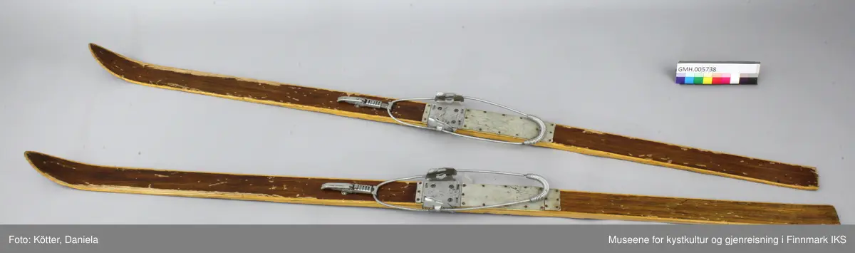 Treskiene er laget av et mørkt treslag i midten og et lyst treslag på kantene. Skiene er transparent lakkert. De har Kandahar - bindinger fra Gresvig som består av justerbare metalldeler og en fjærbånd som føres rund baksiden av skoen. Som skoens underlag er det spikret på grått kunststoff, eventuelt linoleum.  