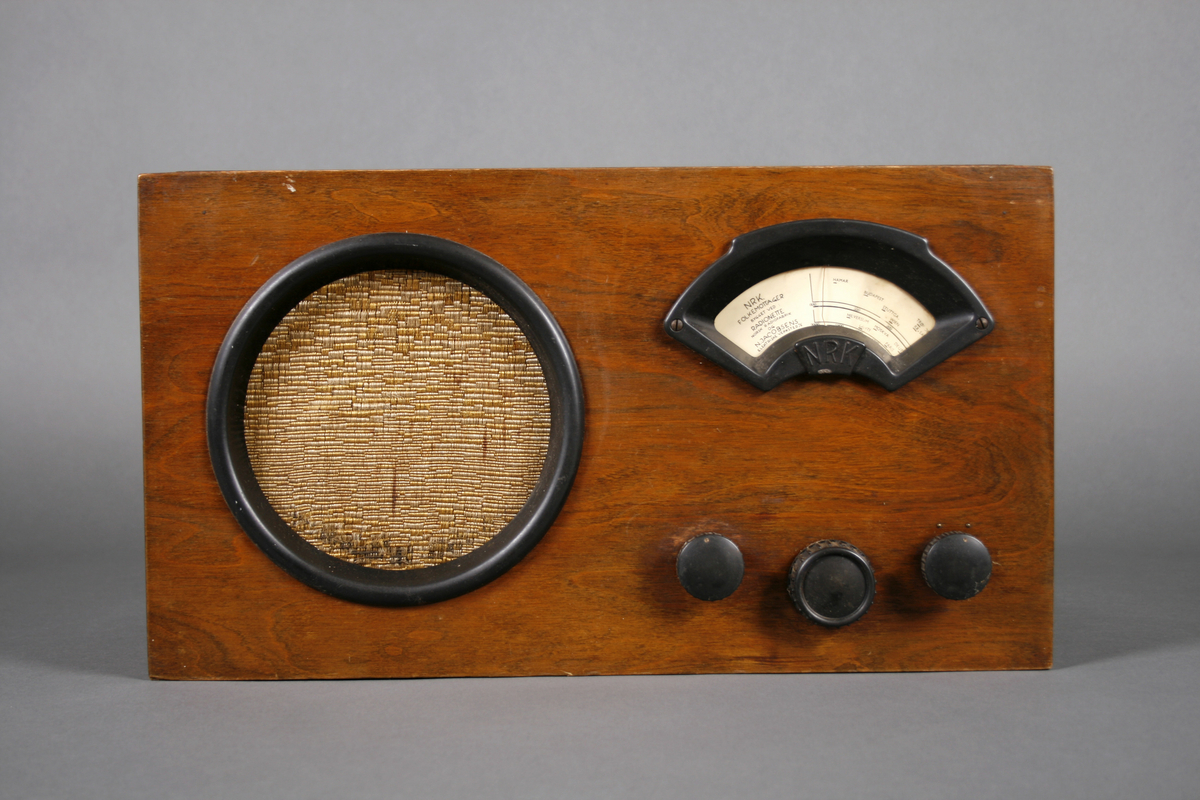 Radio i enkel kasse av finer. Rund høyttaler på venstre side av front. Skala med ramme i bakelitt på høyre side, under dette tre knapper i bakelitt: Volum, innstilling frekvens og av-på. Høyttaleren er omrammet av en ring i bakelitt og trukket med stoff.

Innvendig er apparatet delt i to, tilgang fra baksiden. På høyre side er høyttaleren og på venstre side radiorør og elektronikk med utgang for ledninger.