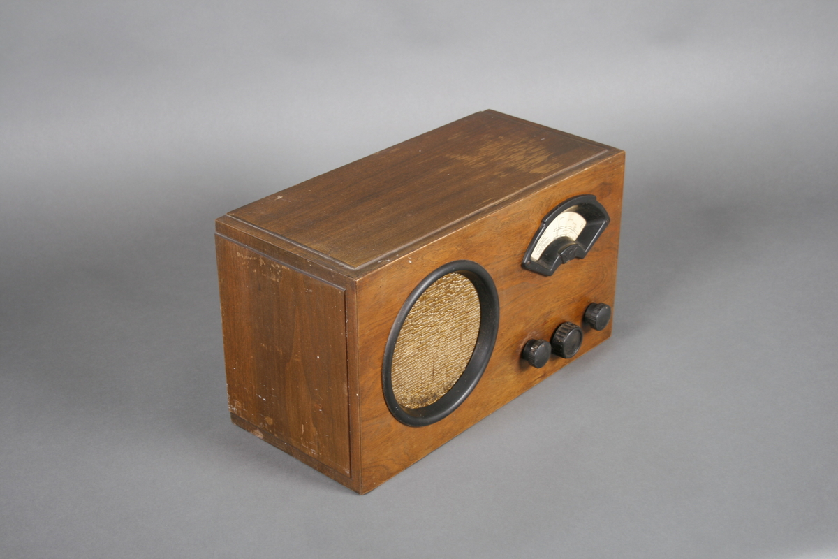 Radio i enkel kasse av finer. Rund høyttaler på venstre side av front. Skala med ramme i bakelitt på høyre side, under dette tre knapper i bakelitt: Volum, innstilling frekvens og av-på. Høyttaleren er omrammet av en ring i bakelitt og trukket med stoff.

Innvendig er apparatet delt i to, tilgang fra baksiden. På høyre side er høyttaleren og på venstre side radiorør og elektronikk med utgang for ledninger.